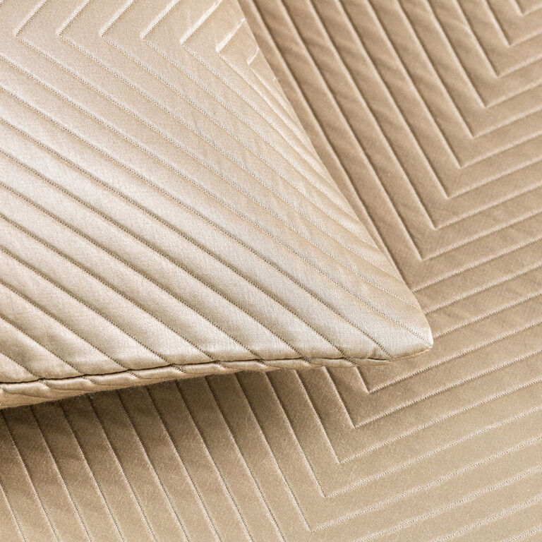 Close-up of a beige Luxe Herringbone | Decorative Sham by Frette with matching diagonal and chevron stitched patterns, perfectly complementing a luxury bedcover.
