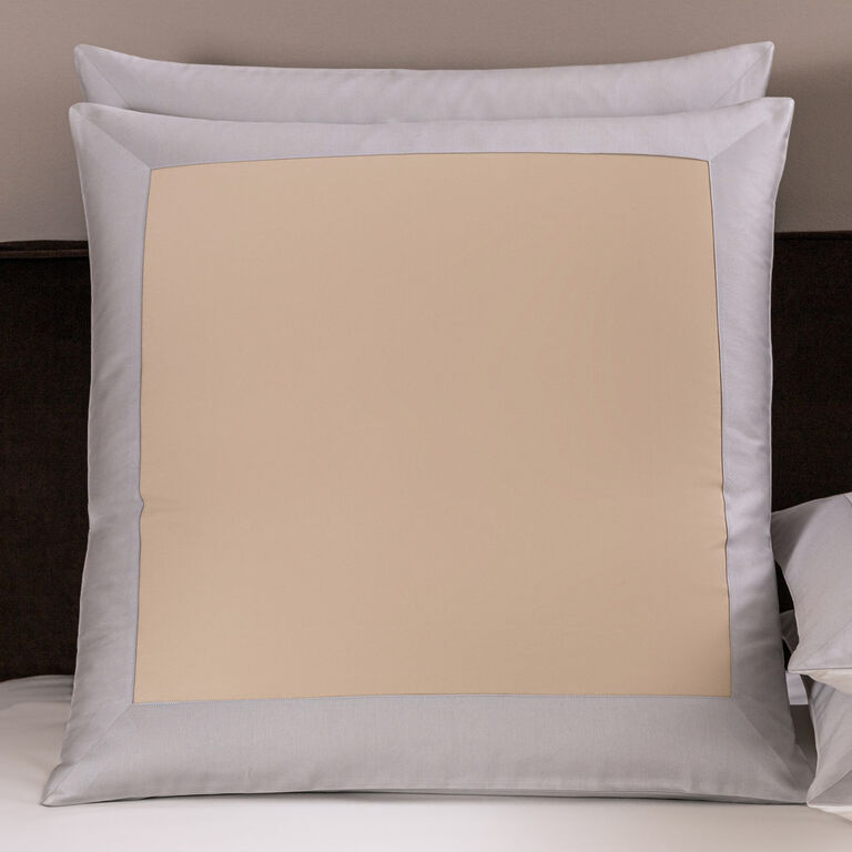 The Frette Rectangular Euro Sham features a light beige center and wide light grey border, styled upright on a bed with a luxurious sham and cotton sateen quilt for an elegant, layered look.