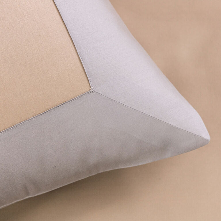 Close-up of the Frette Rectangular | Euro Sham, featuring beige and light gray fabric panels, styled on a matching beige background—a sophisticated addition to any luxurious bedding ensemble.
