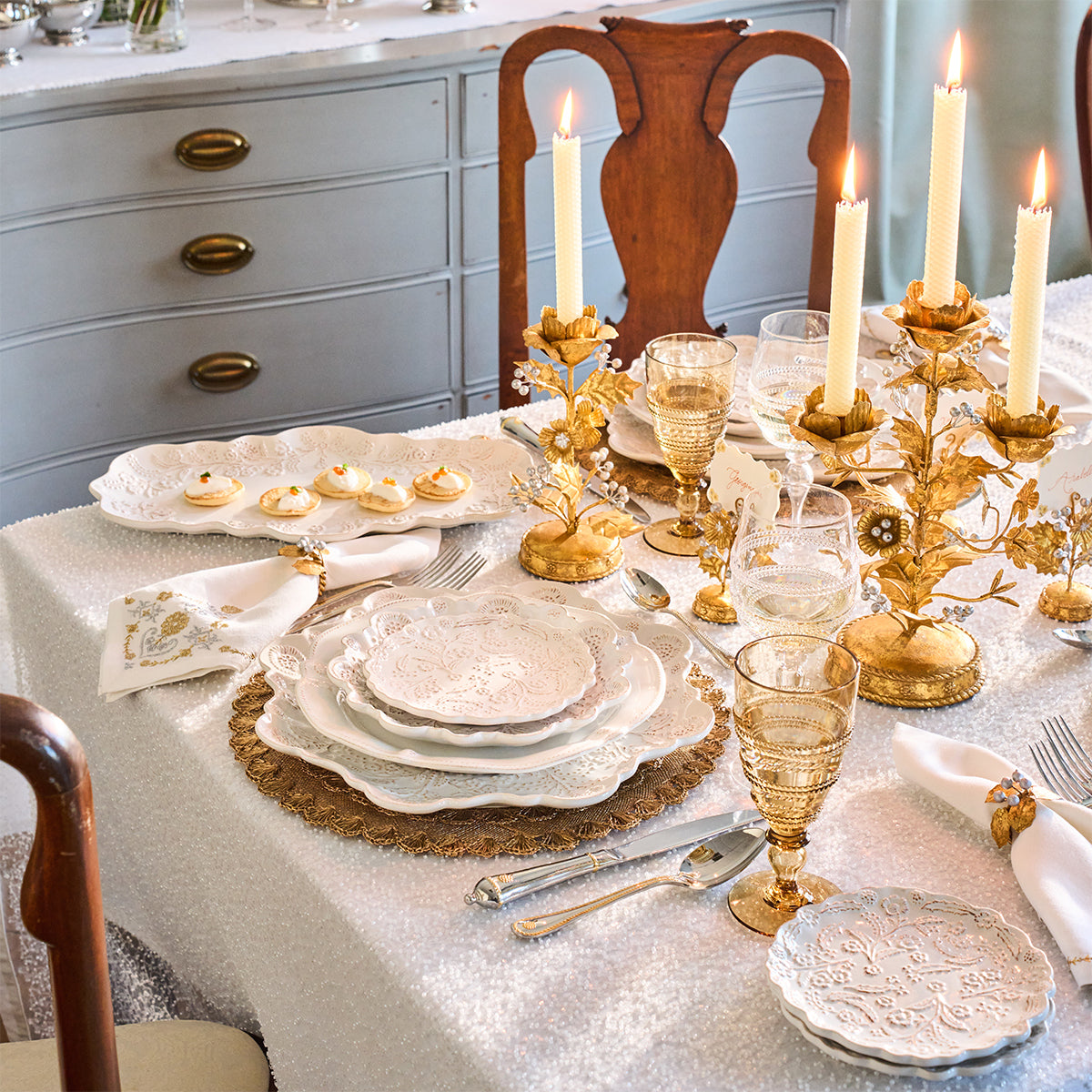 White dining table with gold holly candelabras, scalloped plates and amber glassware