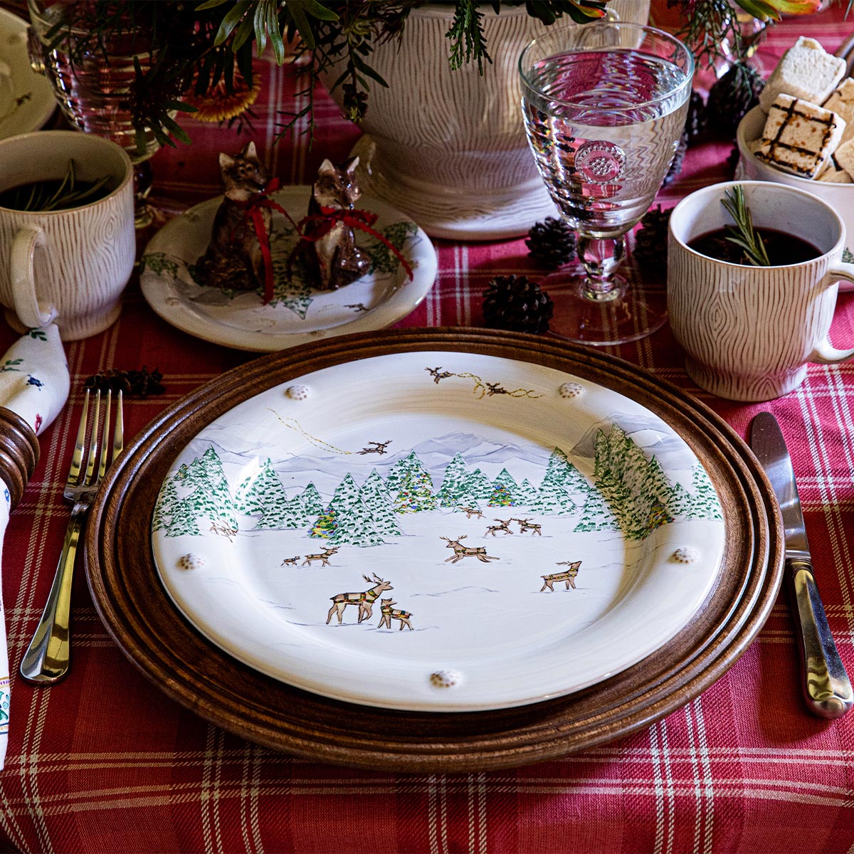 North Pole dinner plate on a woven charger set on a red plaid tablecloth with glassware