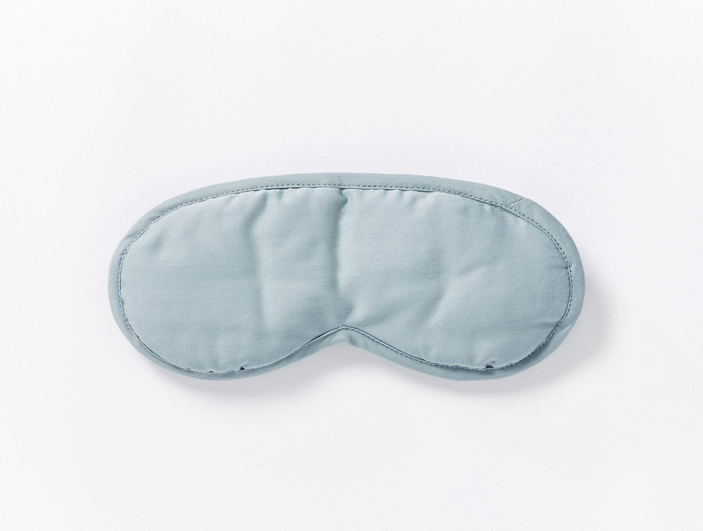 Coyuchi Cloud Soft Sateen eye mask in mist blue, top-down view on white background.