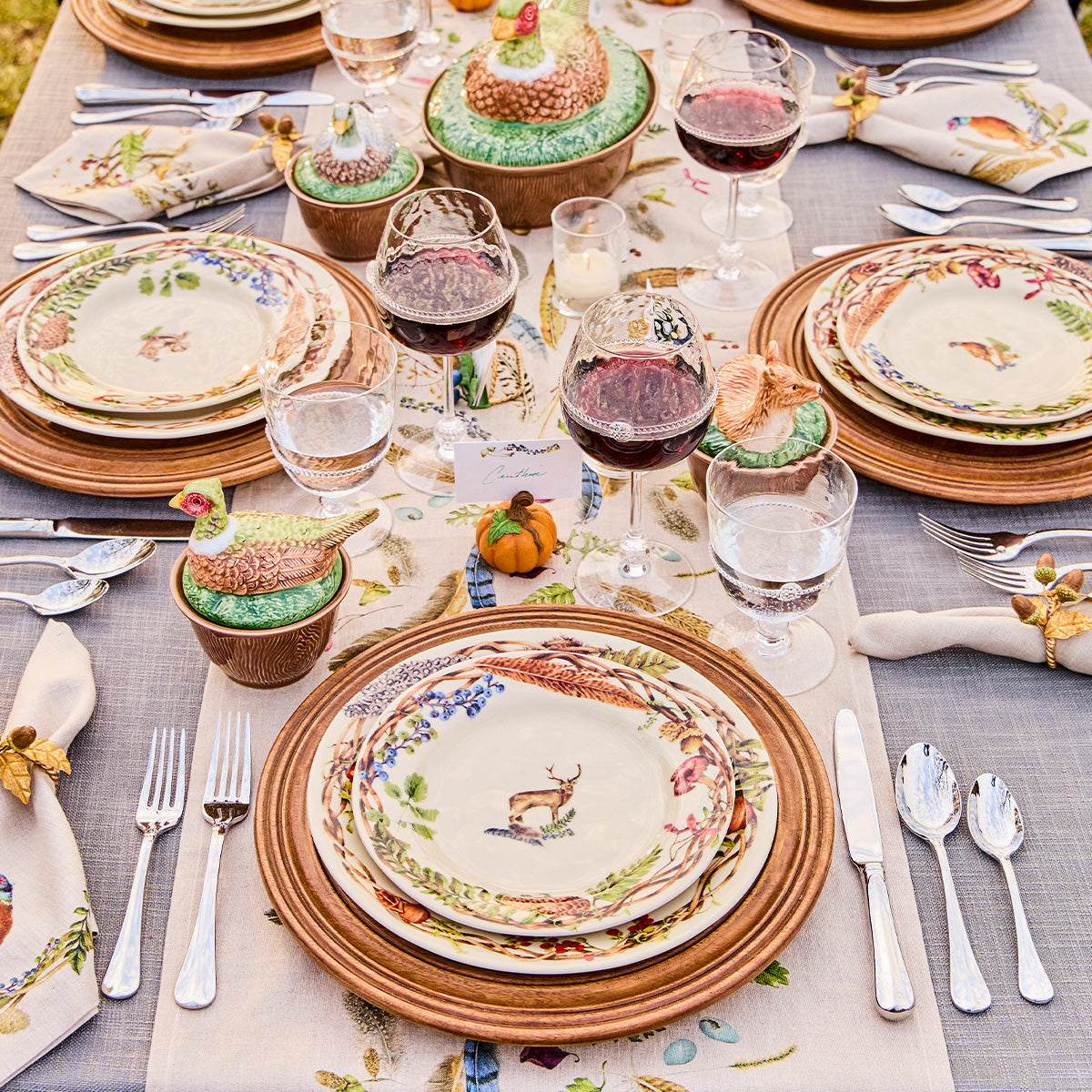 Outdoor table set with Forest Walk stag salad plates on wicker chargers with wine glasses