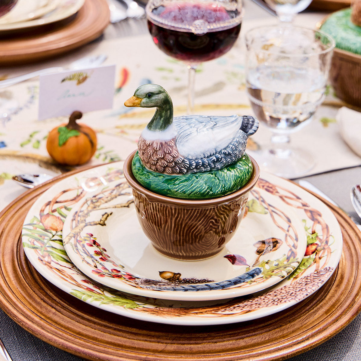 Forest Walk duck lidded bowl on stacked Forest Walk plates with a wine glass and a small pumpkin