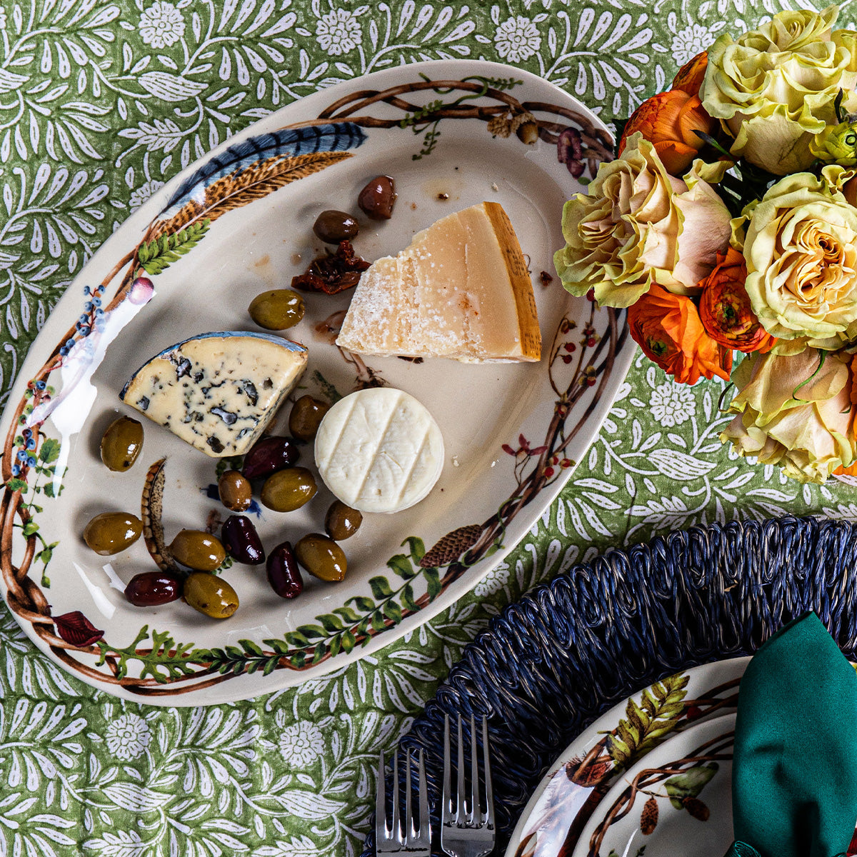 Forest Walk Gratitude platter with cheese, olives and grapes on a green print cloth beside roses