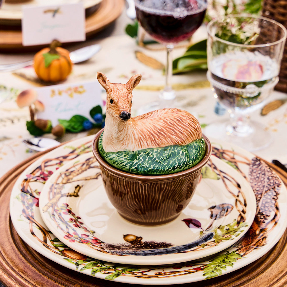 Forest Walk deer lidded bowl on stacked Forest Walk plates with wine glasses and a small pumpkin