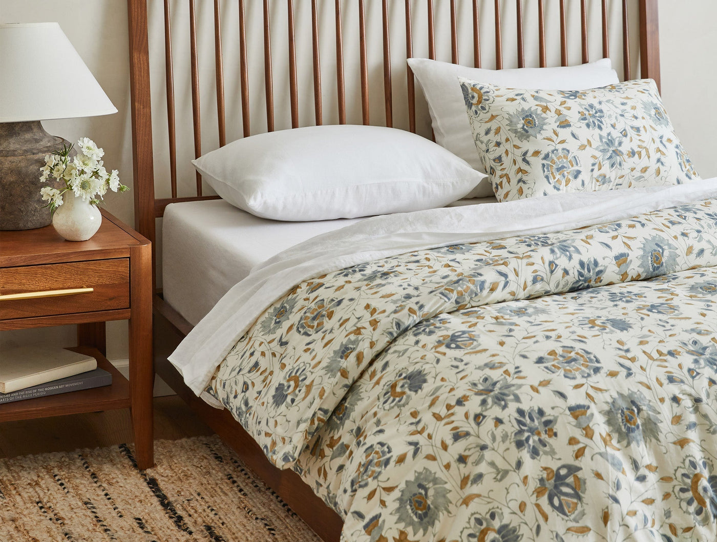 Duvet cover draped on bed showing full floral print in blue, gold, and ivory tones.