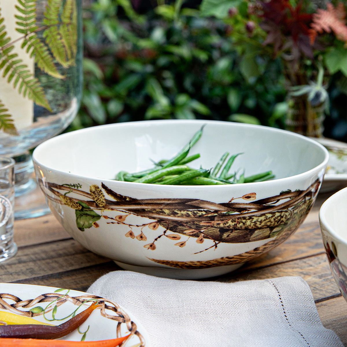 Forest Walk 10 inch serving bowl with green beans on an outdoor table with ferns