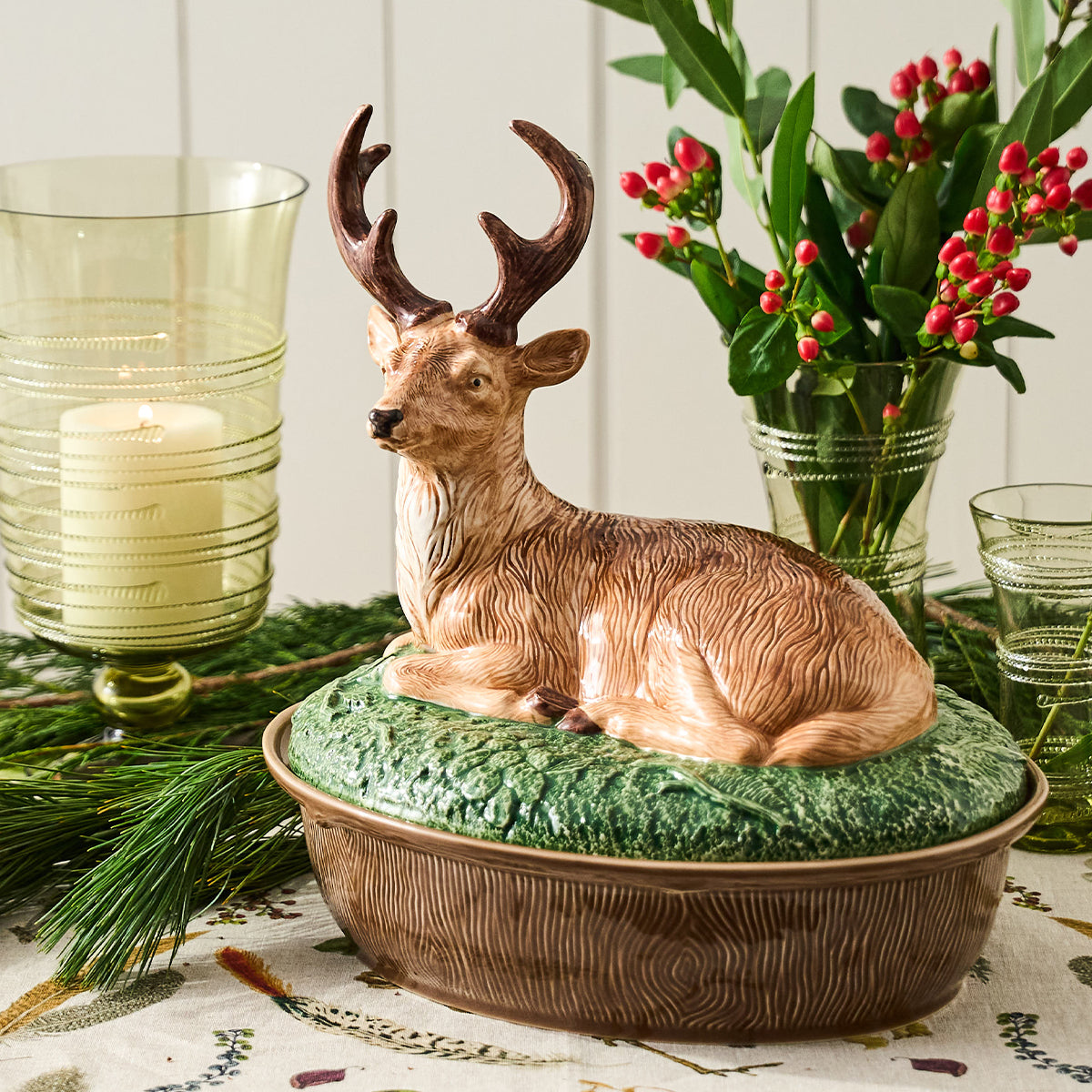 Forest Walk stag lidded baker on a table with pine, holly berries and a glass candle holder