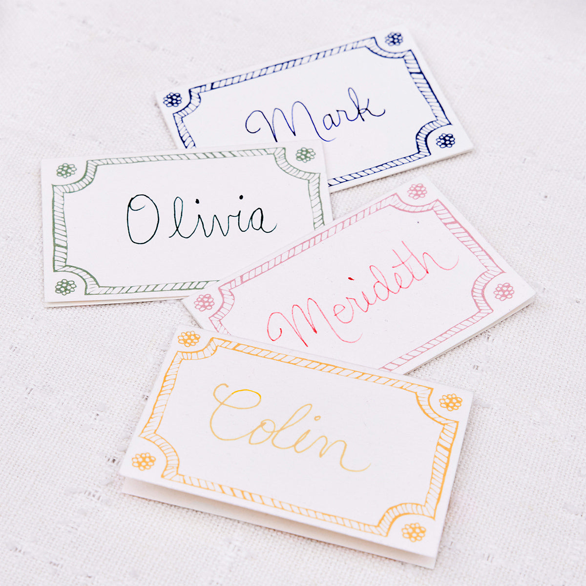 Berry & Thread place cards with handwritten names in several border colors