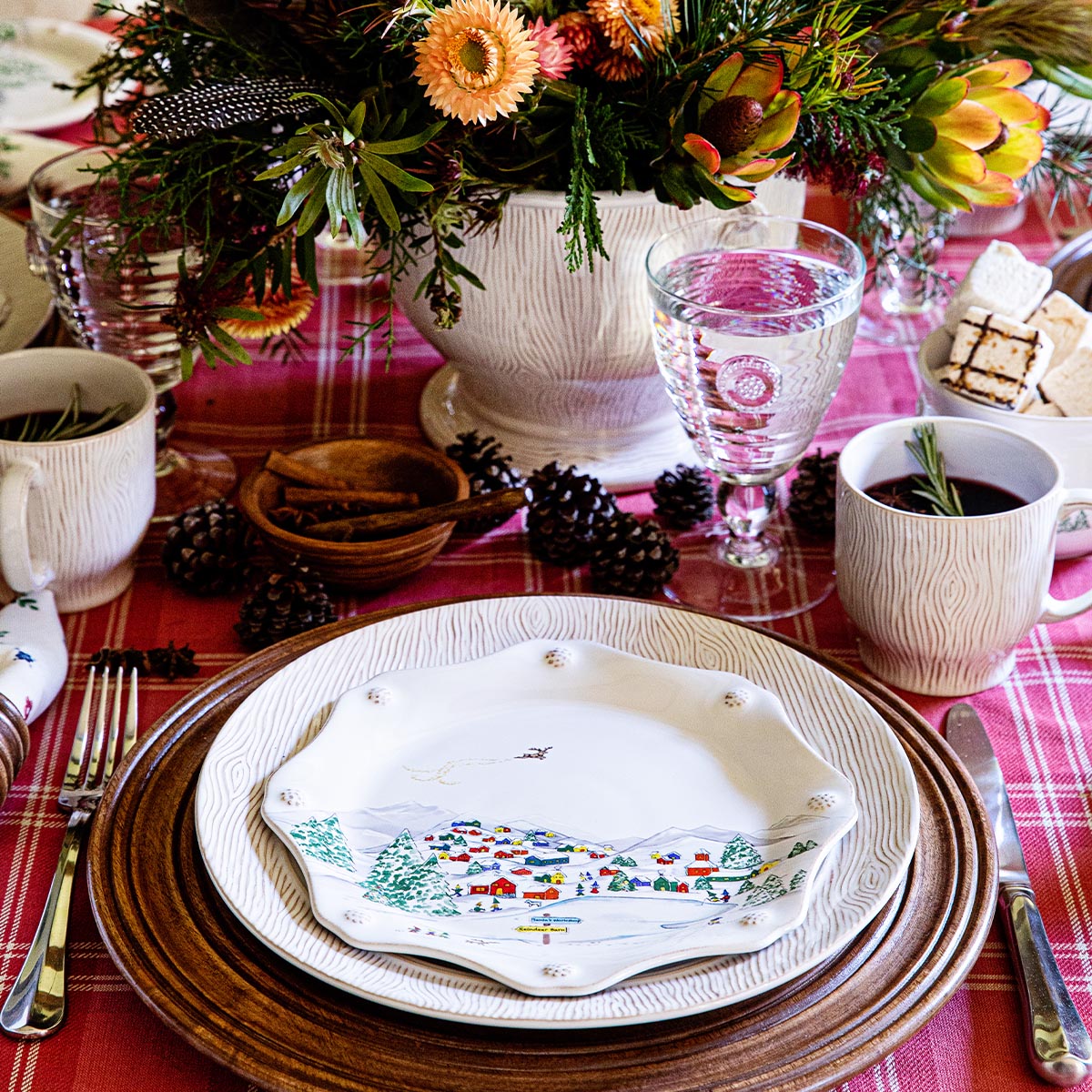 North Pole salad plate stacked on a dinner plate and woven charger beside a holiday centerpiece