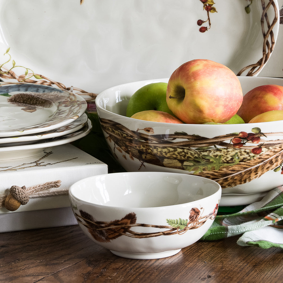 Forest Walk berry bowl in front of a larger Forest Walk bowl of apples on a wood table