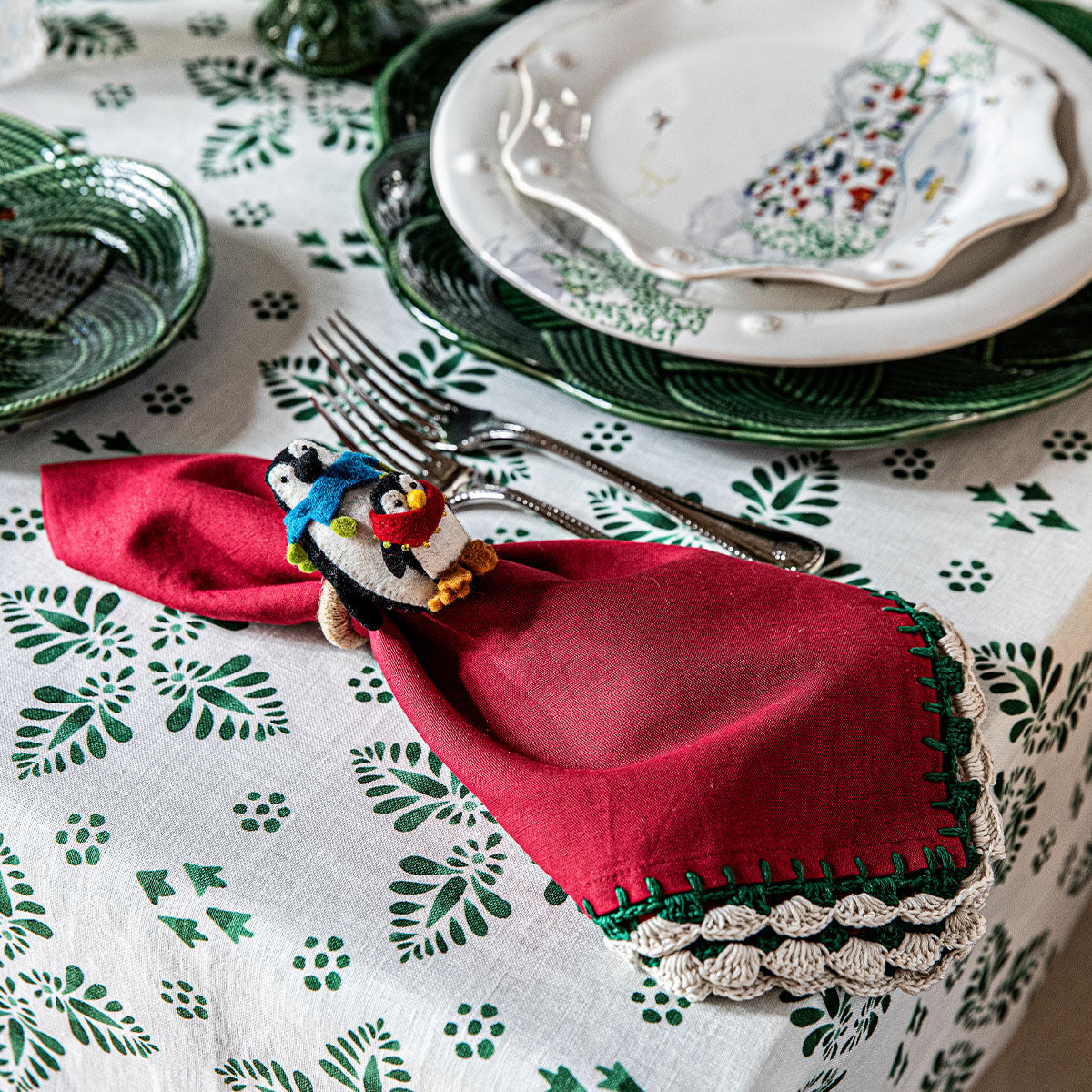 Red napkin in a felt penguin napkin ring beside a place setting