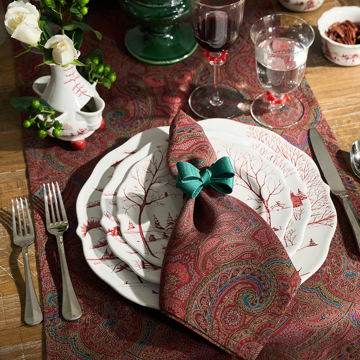 Ruby Winter Frolic charger under a plate and paisley napkin with a green bow