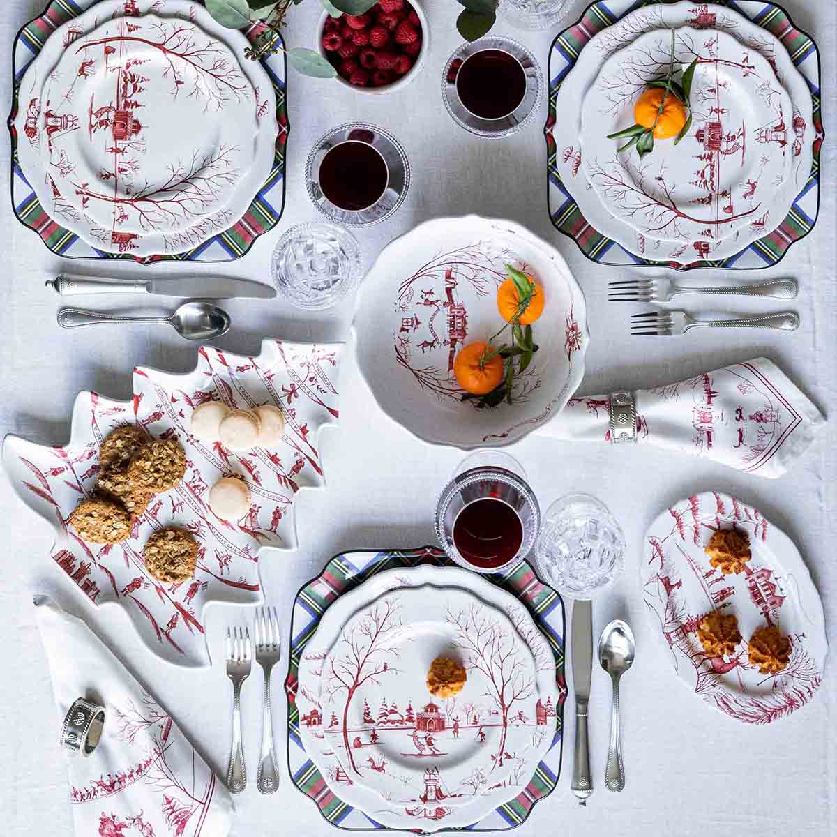 Overhead table set with ruby Winter Frolic plates, bowls and holiday sweets