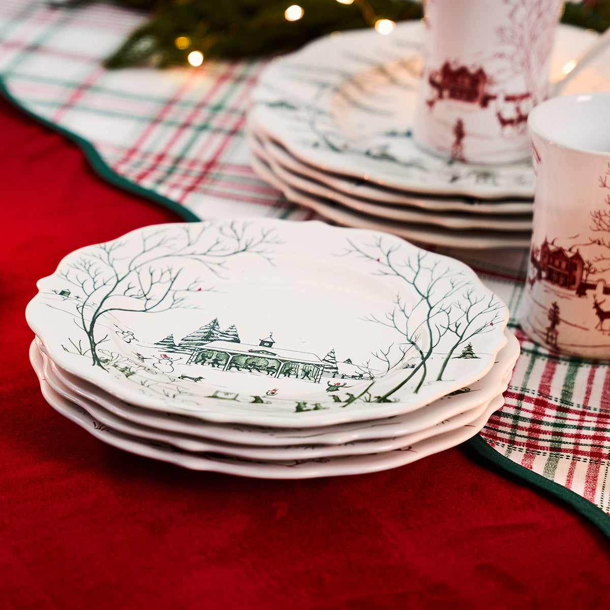 Stack of evergreen Winter Frolic salad plates on a red tablecloth