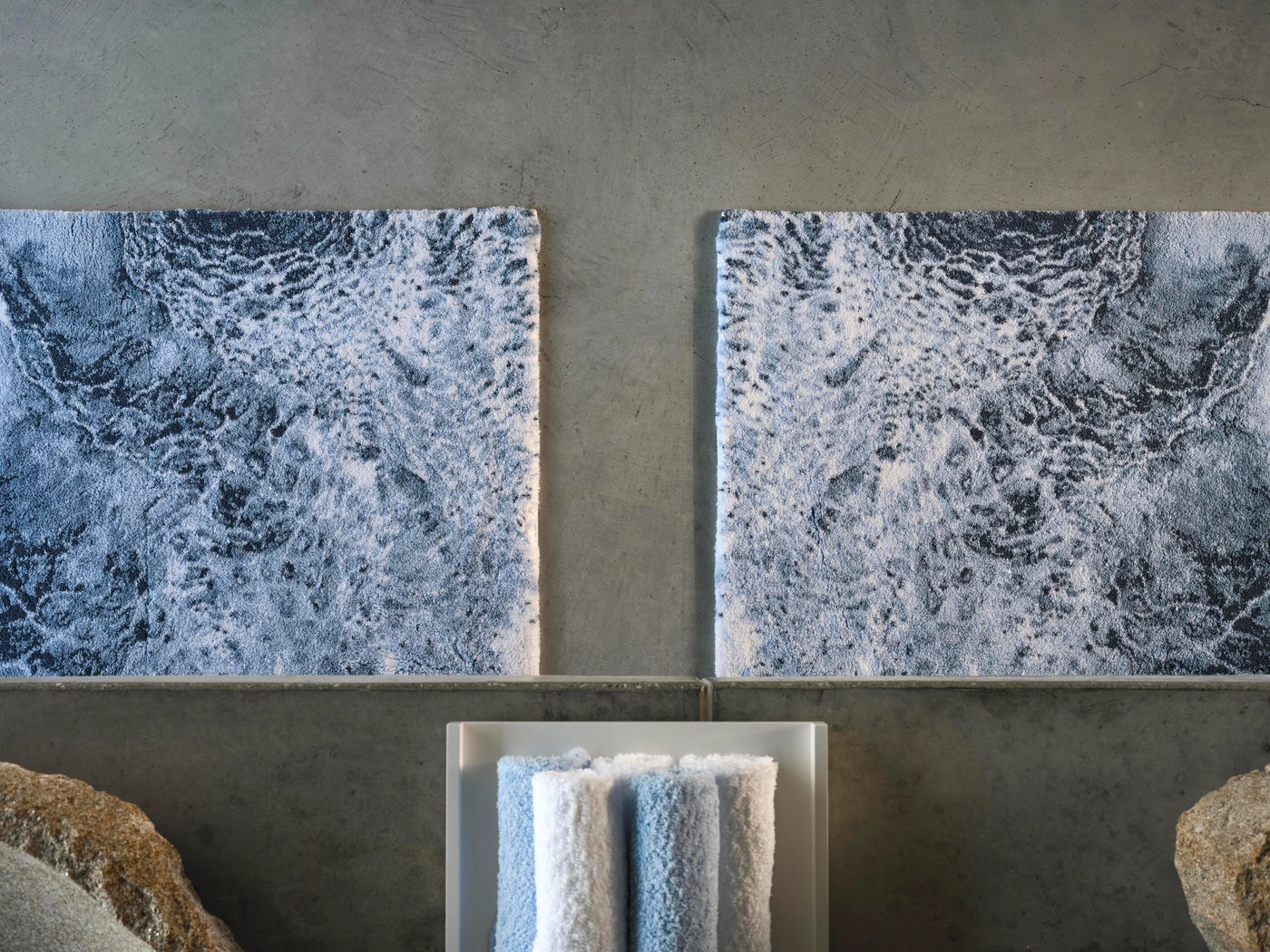Close-up overhead view of two Abyss Habidecor Nazare rugs in indigo wave pattern side by side.