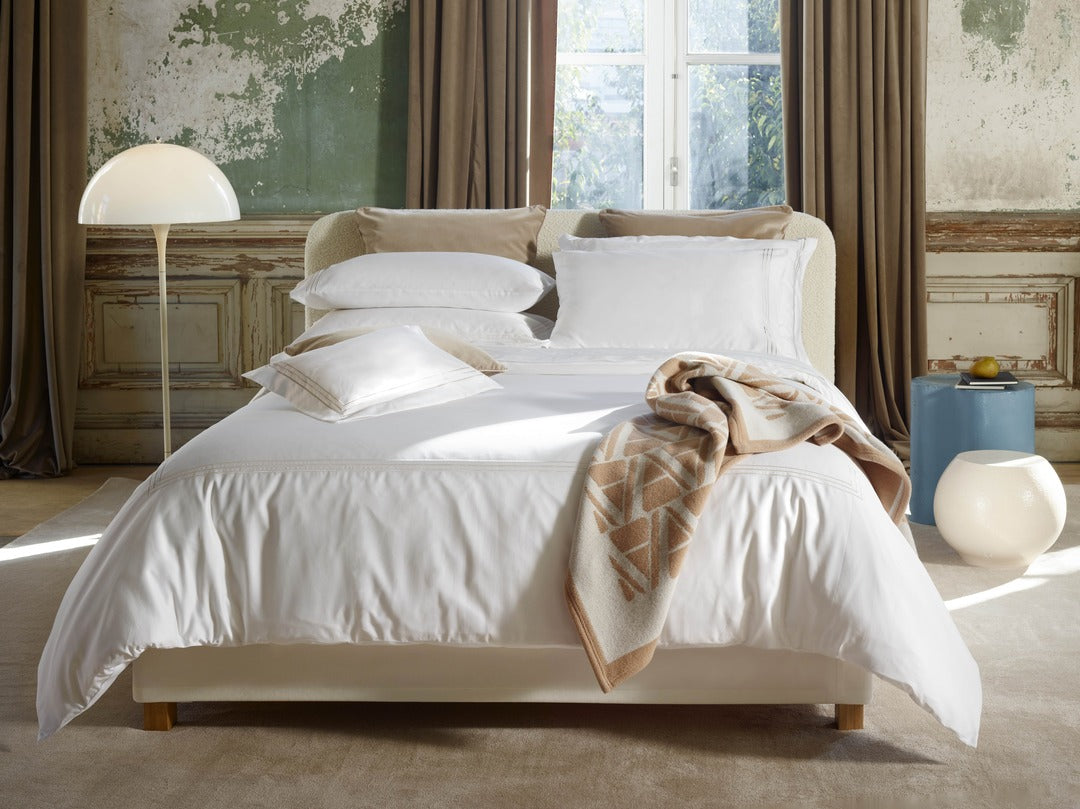 White Alvorada duvet cover styled on a bed with a camel plaid throw.