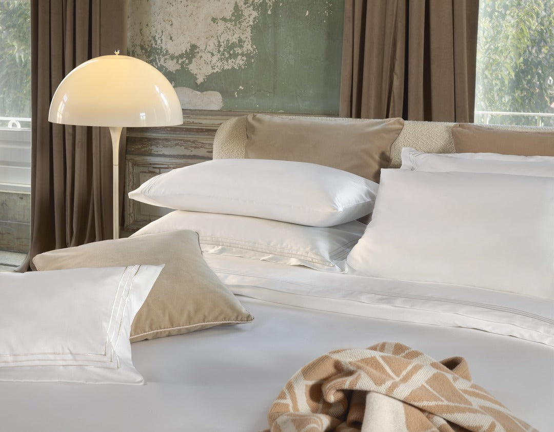 Close-up of white Alvorada duvet cover styled with sand cushions and geometric throw.