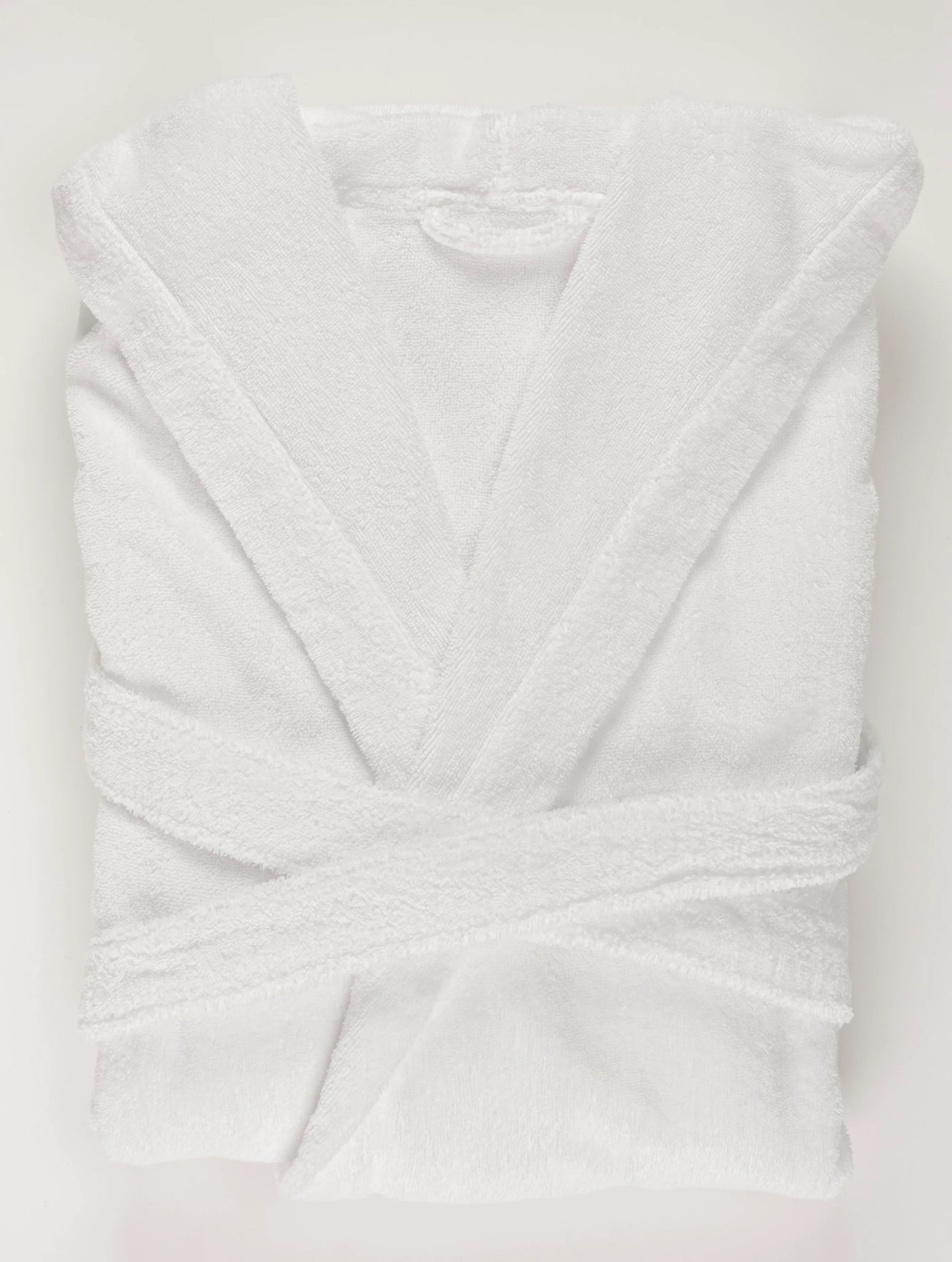 Folded white terry cloth robe with crossed belt, shot from above.