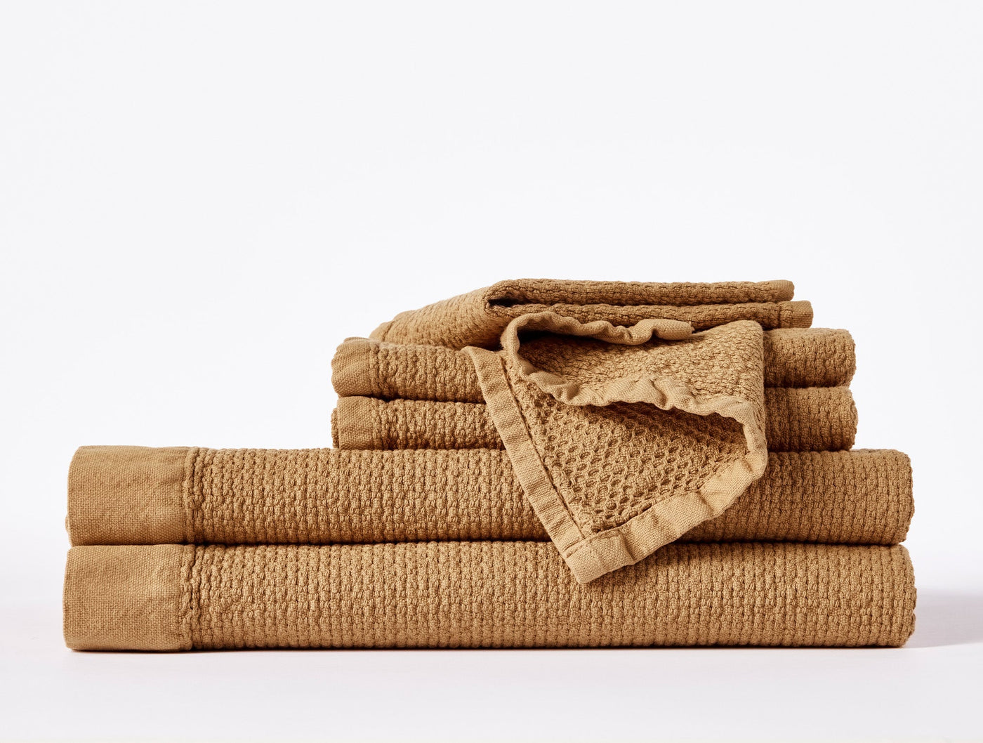 Stacked caramel waffle-weave bath towels with ruffled trim detail.