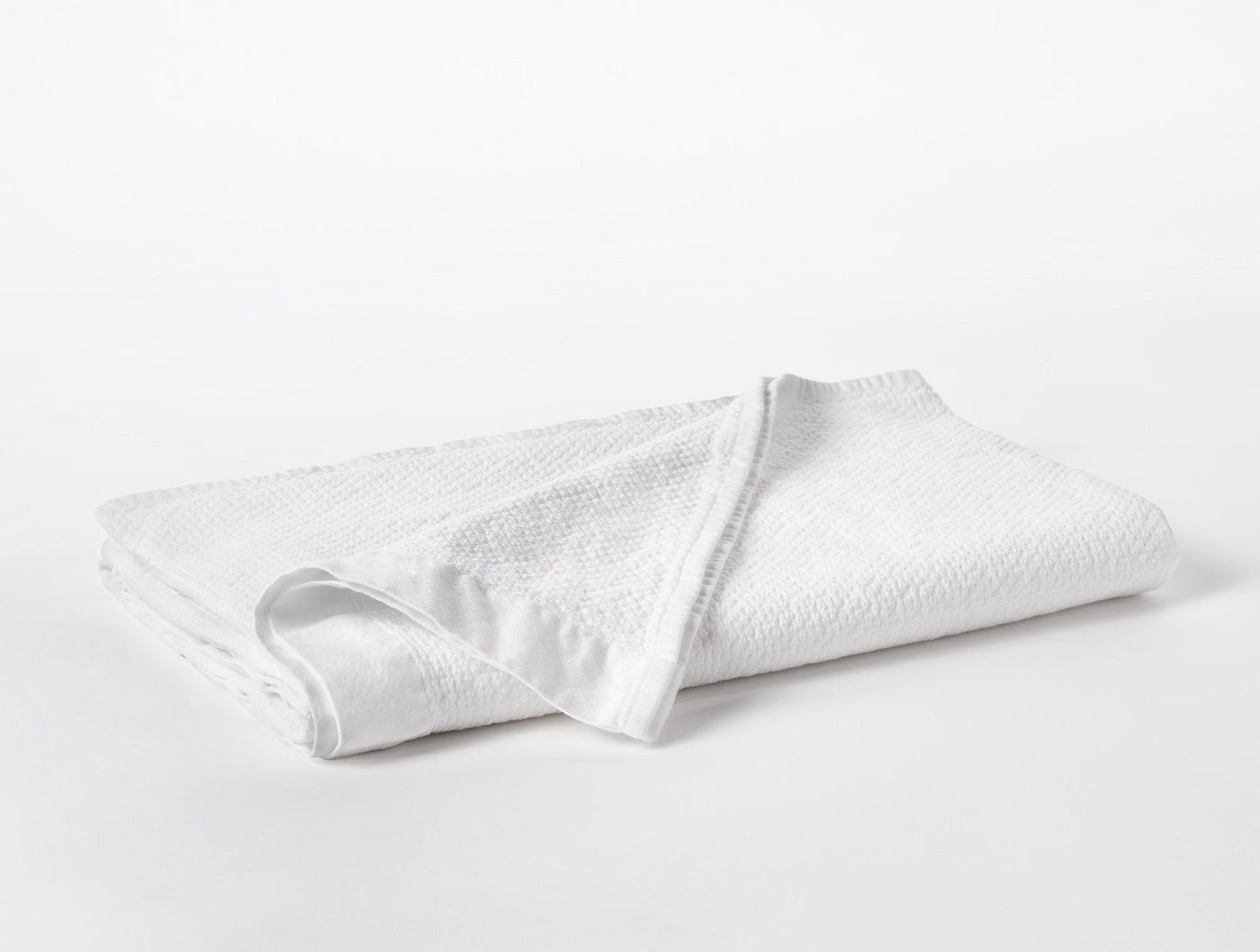Folded white Coyuchi Adriatic towel showing textured waffle weave surface detail.