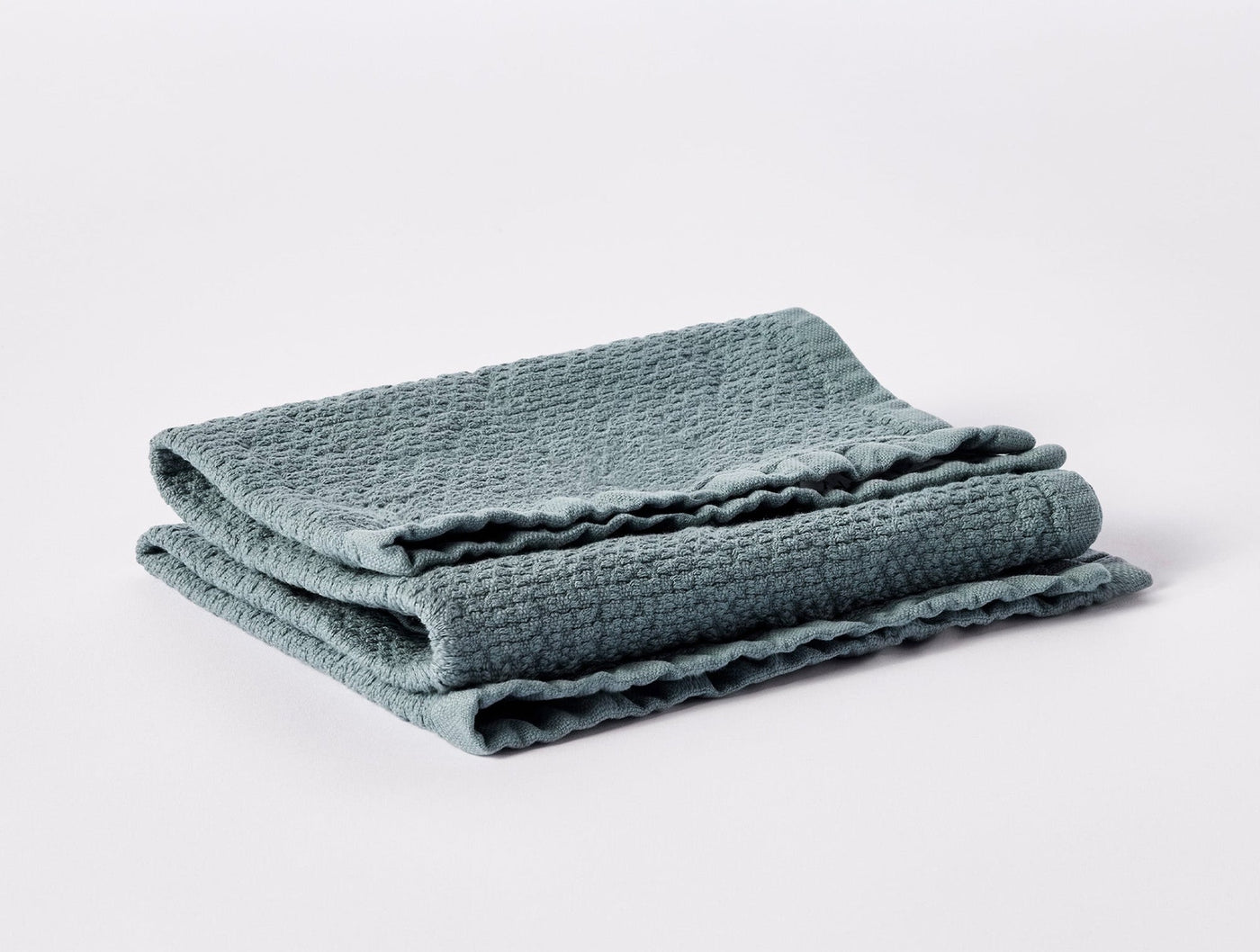 Folded seafoam waffle-weave towel showing scalloped edge trim detail.
