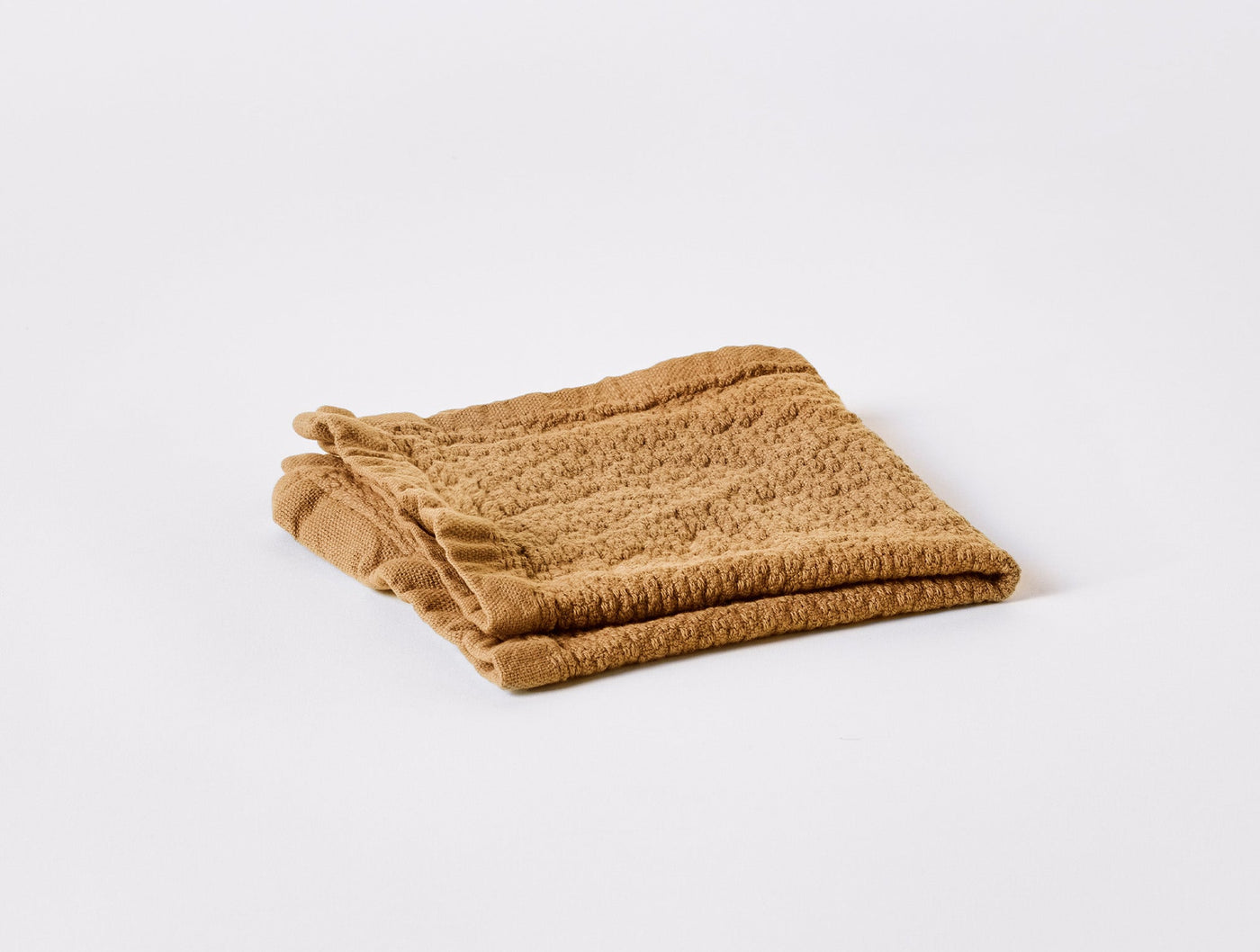 Coyuchi Adriatic bath towel in ochre, folded flat showing fringe edge detail.
