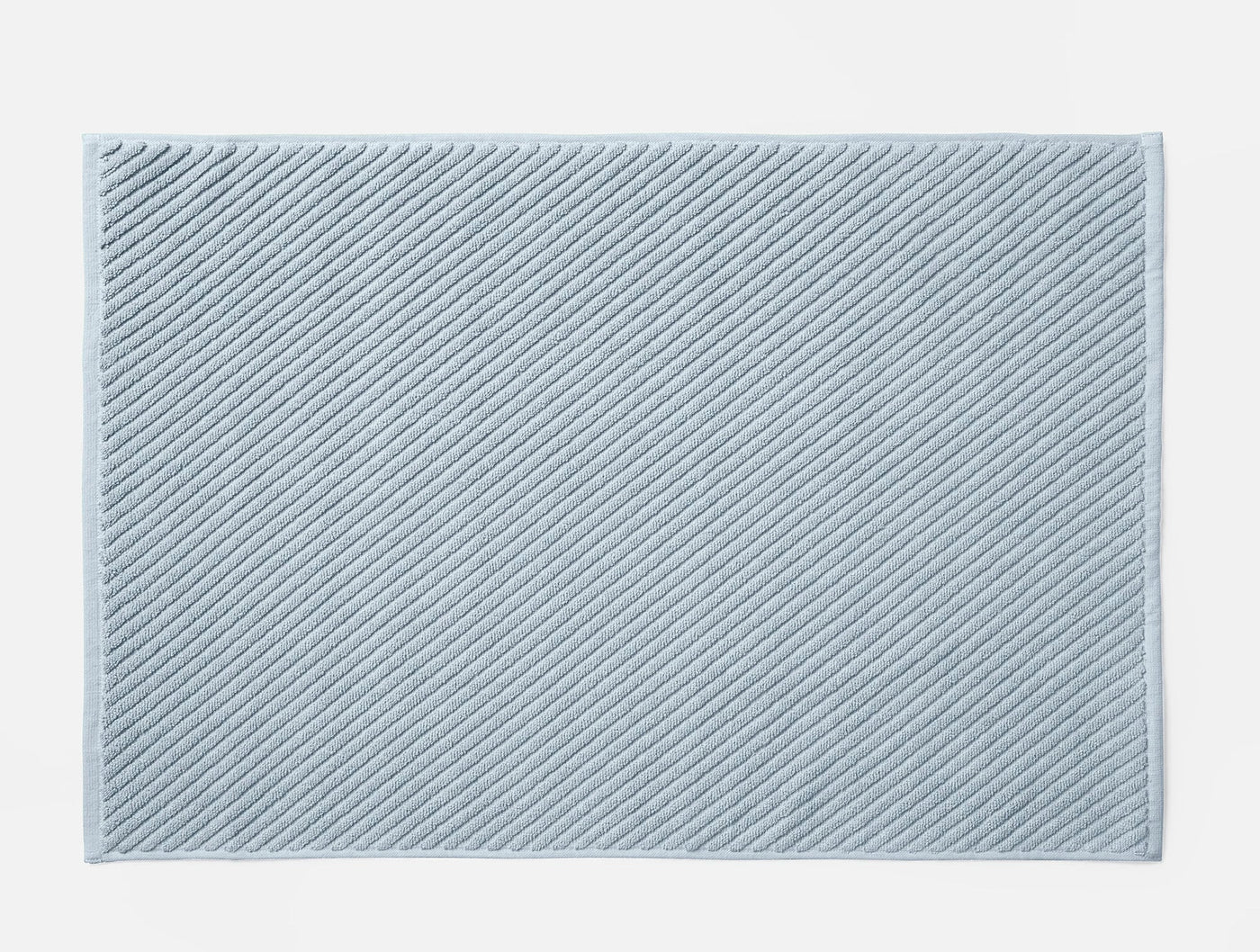 Close-up of Coyuchi Air Weight bath rug in pale blue with diagonal ribbed twill texture.