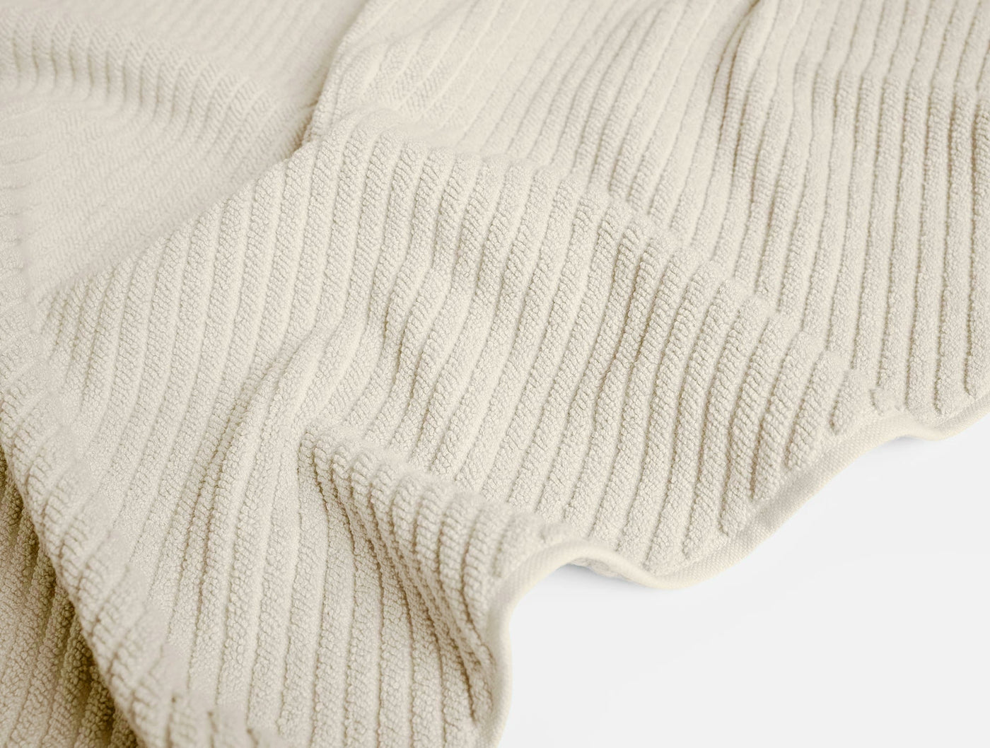 Close-up of ivory Coyuchi Air Weight bath rug showing ribbed cotton weave texture.