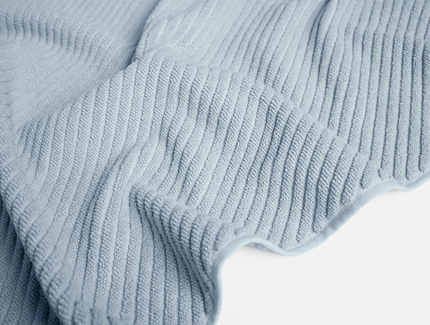 Close-up of pale blue ribbed cotton weave texture with soft draping folds.