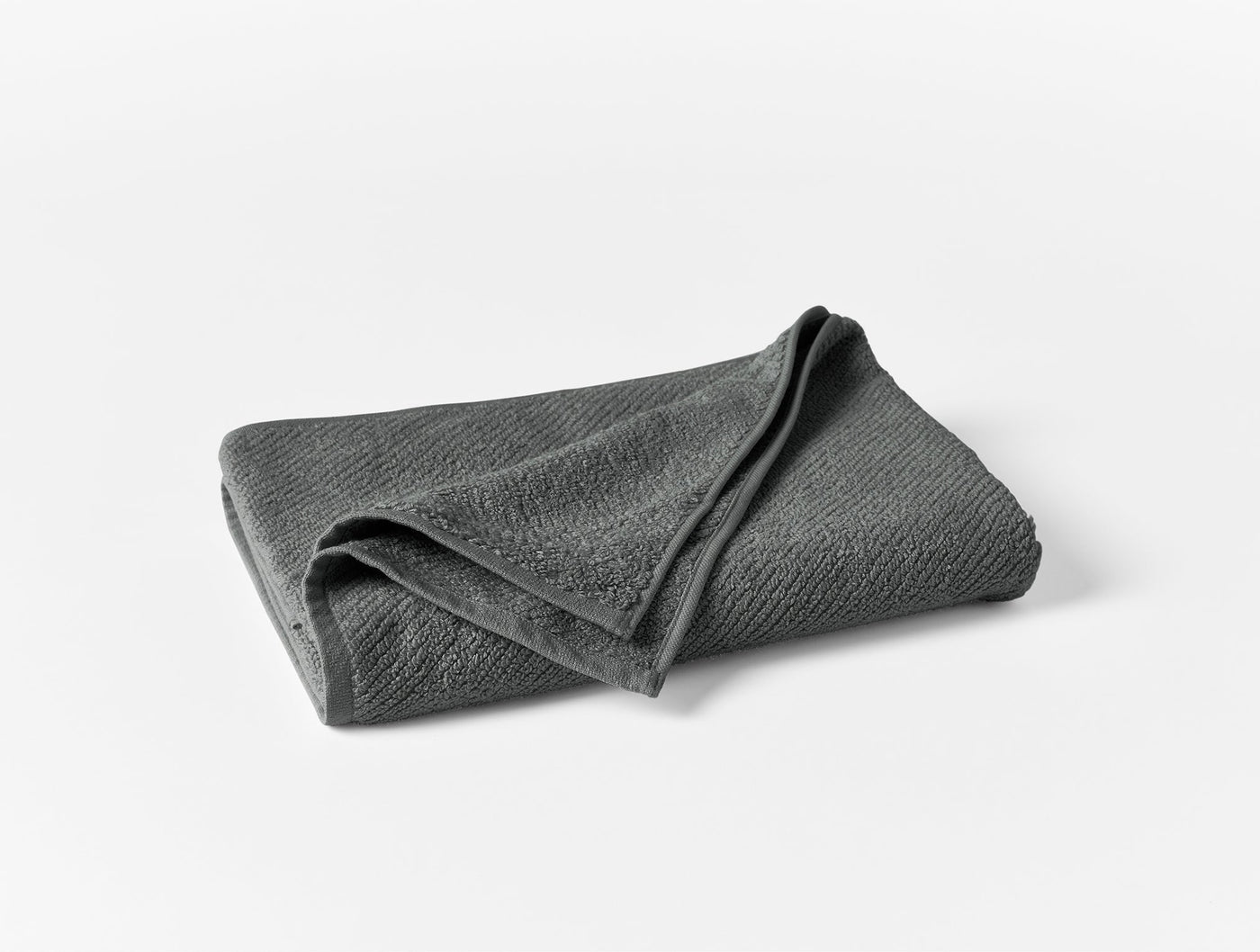 Coyuchi Air Weight bath sheet folded, charcoal gray textured weave on white background.