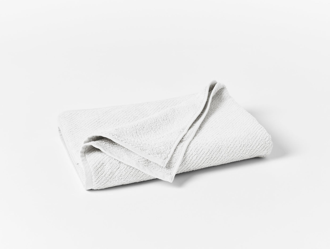 Coyuchi Air Weight oversized hand towel folded, white textured cotton weave.