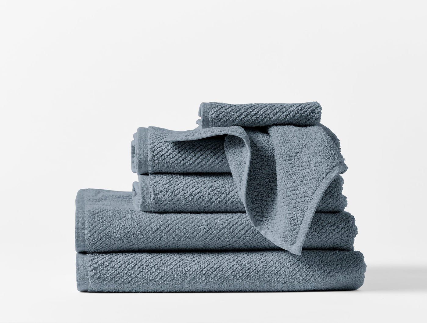 Coyuchi Air Weight towel set stacked in slate blue, showing textured weave detail.
