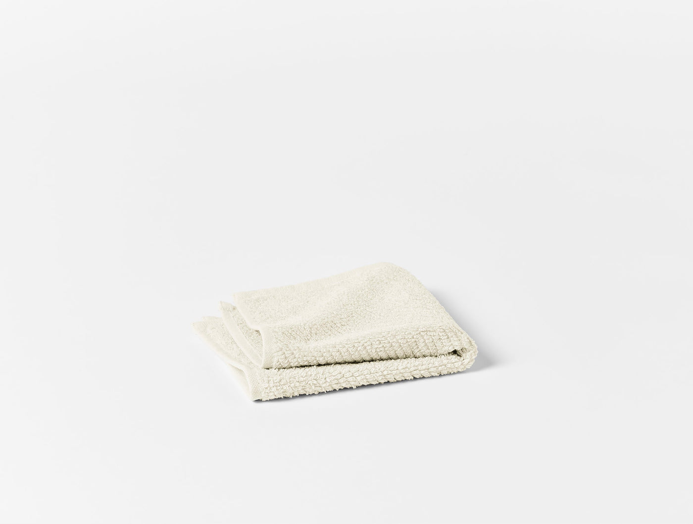 Folded ivory terry bath sheet showing plush looped texture, photographed on white background.