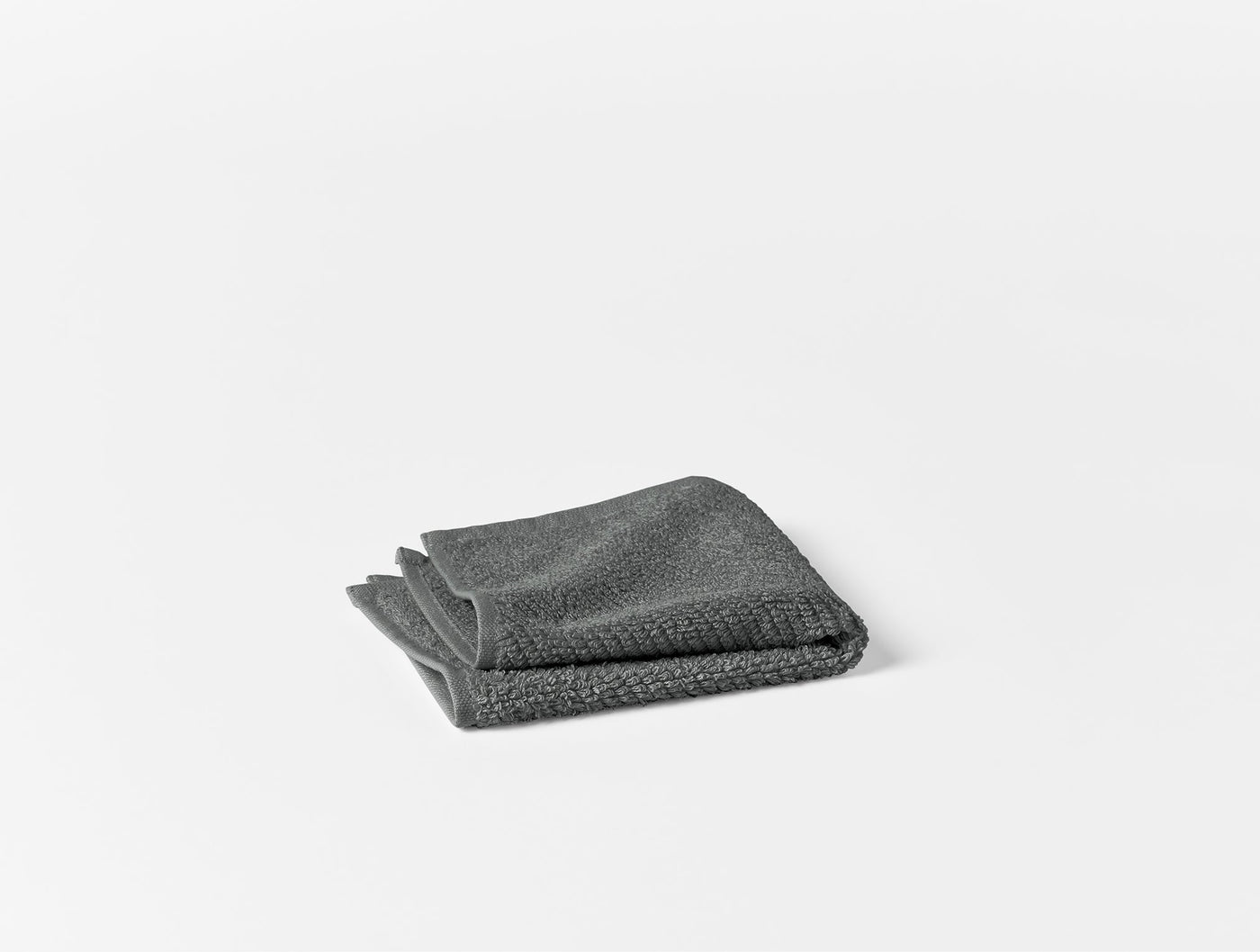 Slate grey folded washcloth with textured waffle weave, shown against white background.