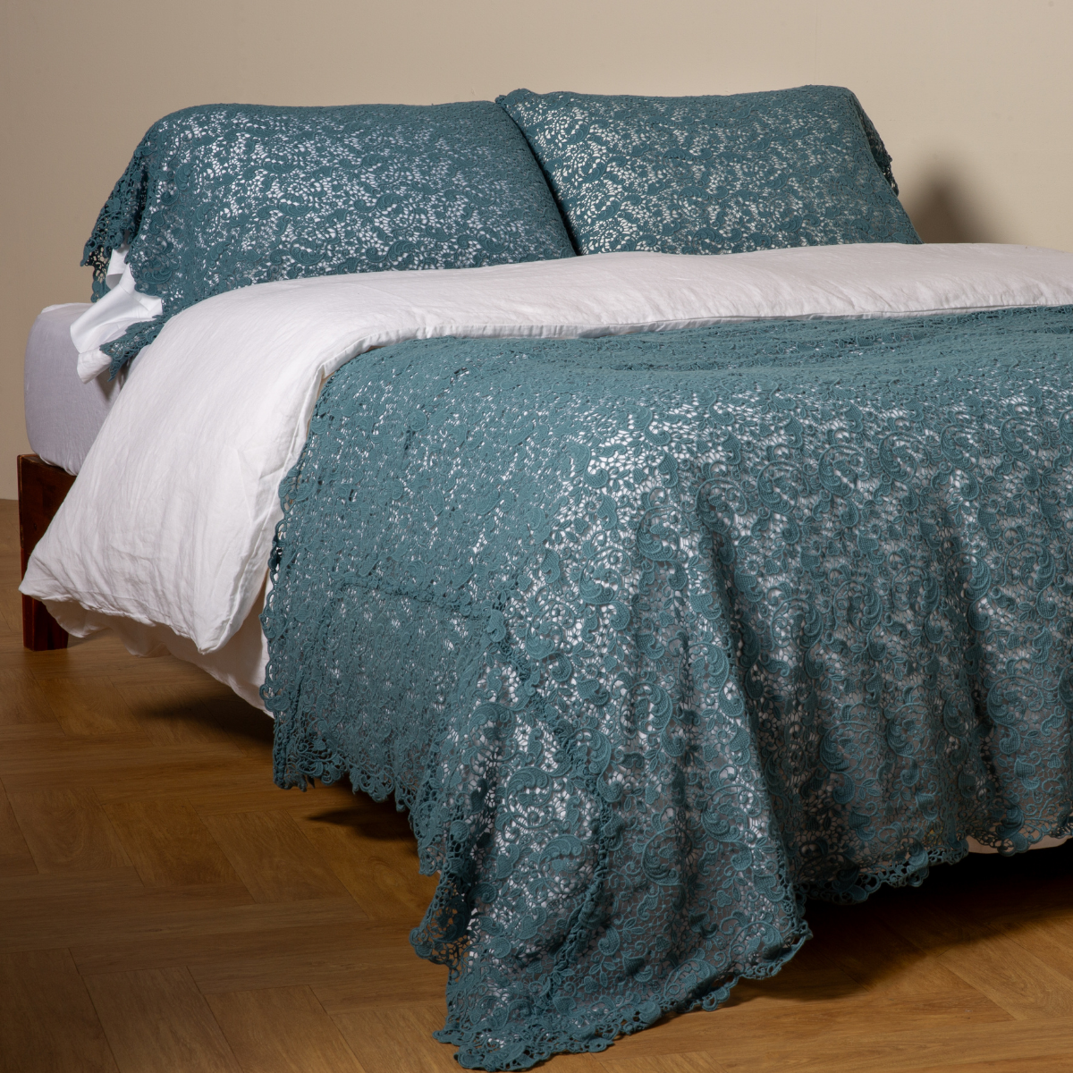Bella Notte Allora bed scarf in Cenote draped over bed with matching pillow shams, lace detail visible.