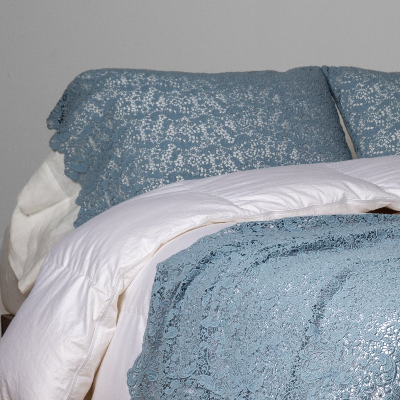 Tahoe Blue lace-textured bed scarf draped over white bedding, styled at foot of bed.