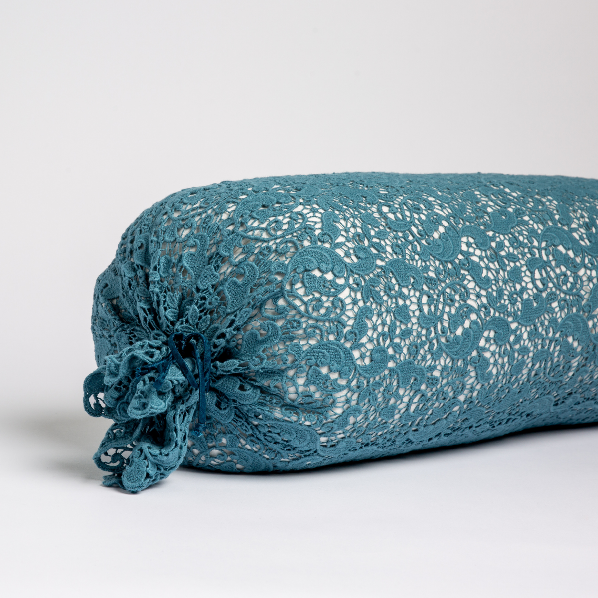 Cenote lace bolster throw pillow with gathered end detail, close-up side angle.