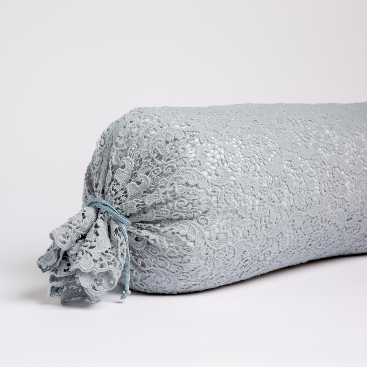 Close-up of Cloud Allora Lace bolster pillow end with gathered lace trim and ribbon tie.