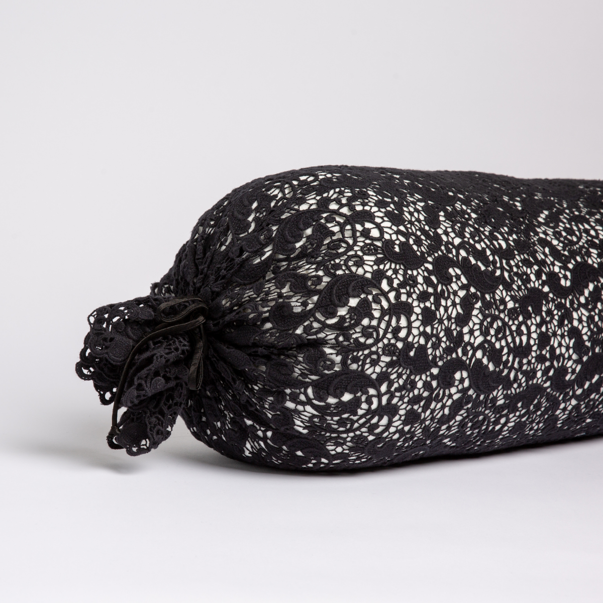 Side angle of Corvino Allora Lace bolster pillow with gathered lace ends and floral lace pattern.