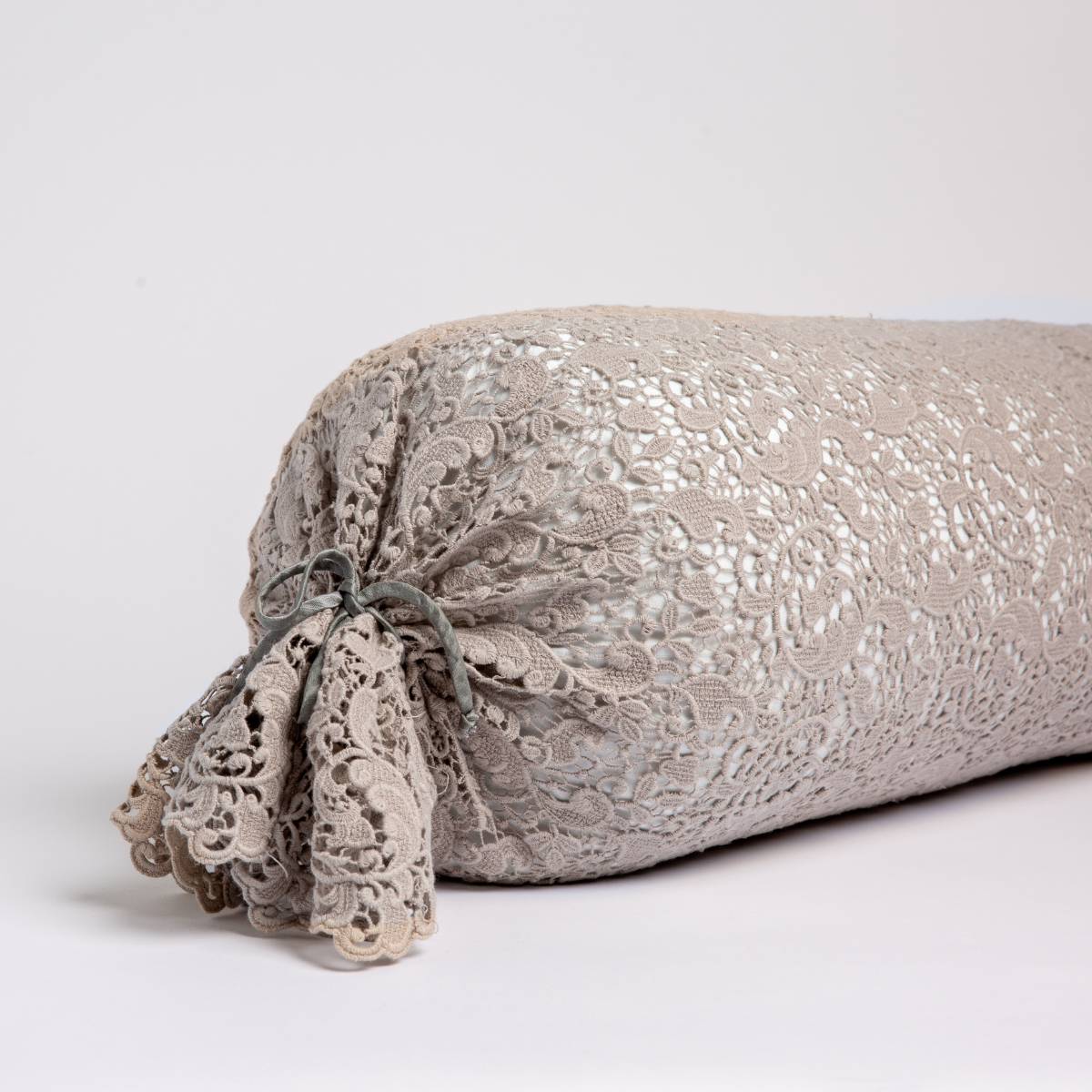 Close-up of Fog Bella Notte Allora Lace bolster pillow with gathered lace tassel end detail.