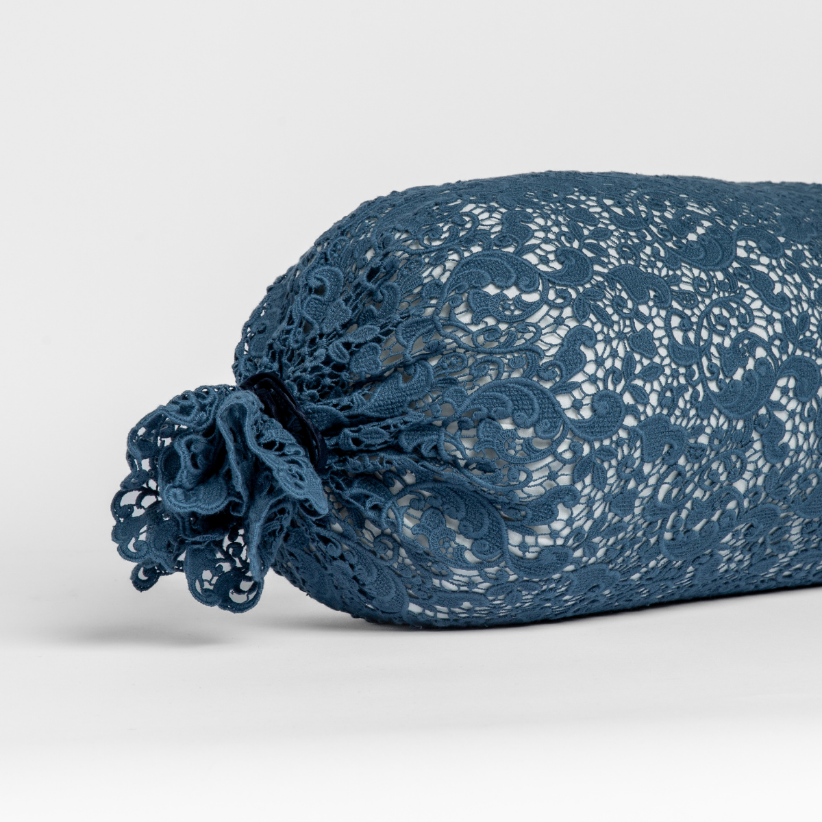 Midnight lace bolster throw pillow with gathered ruched end detail, angled side view.