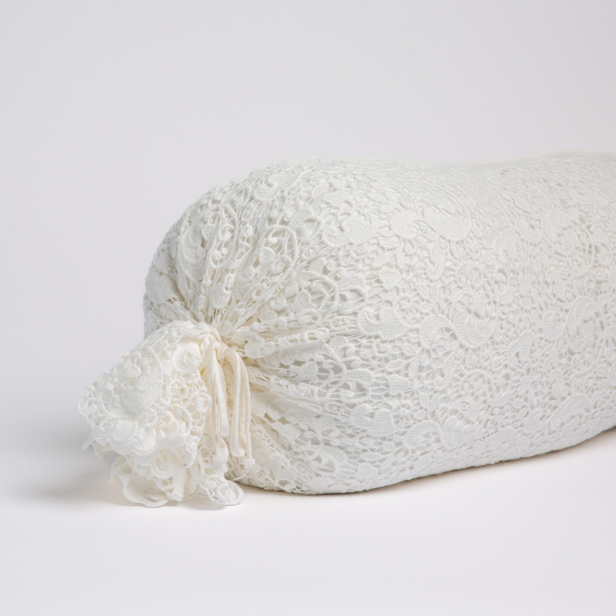 Close-up of Winter White lace bolster pillow with ruffled tie end detail.