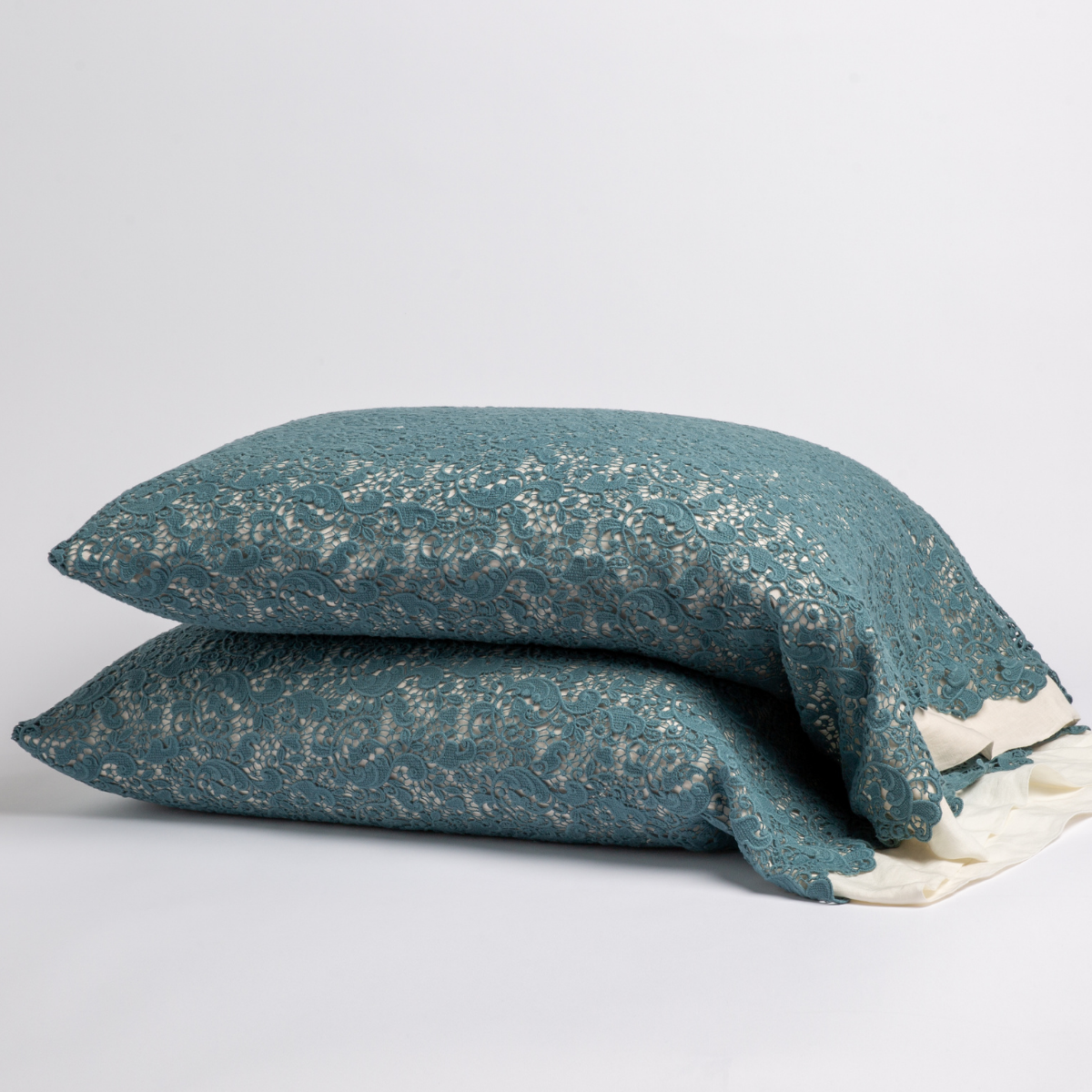 Two Cenote Allora Lace pillowcases stacked, teal lace overlay with ivory underlining visible at corner.
