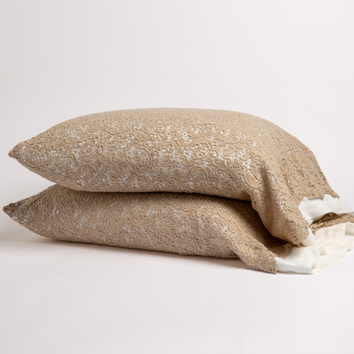 Honeycomb lace pillowcases stacked, showing intricate floral lace texture with ivory lining detail.