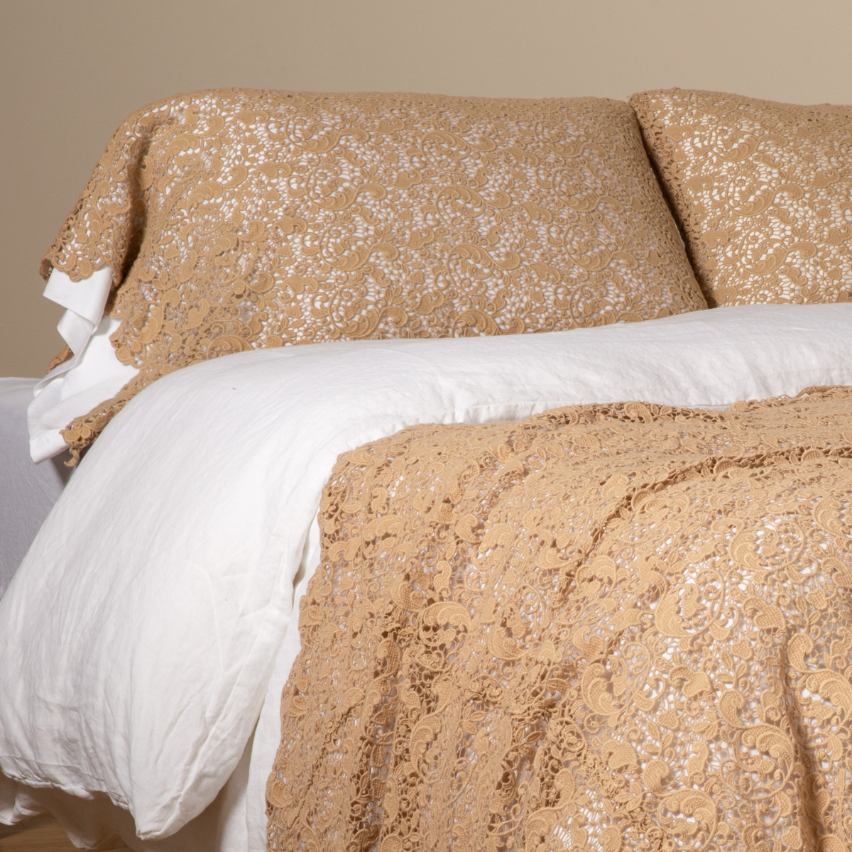 Honeycomb lace pillowcase and coverlet styled on a bed with white linen duvet.