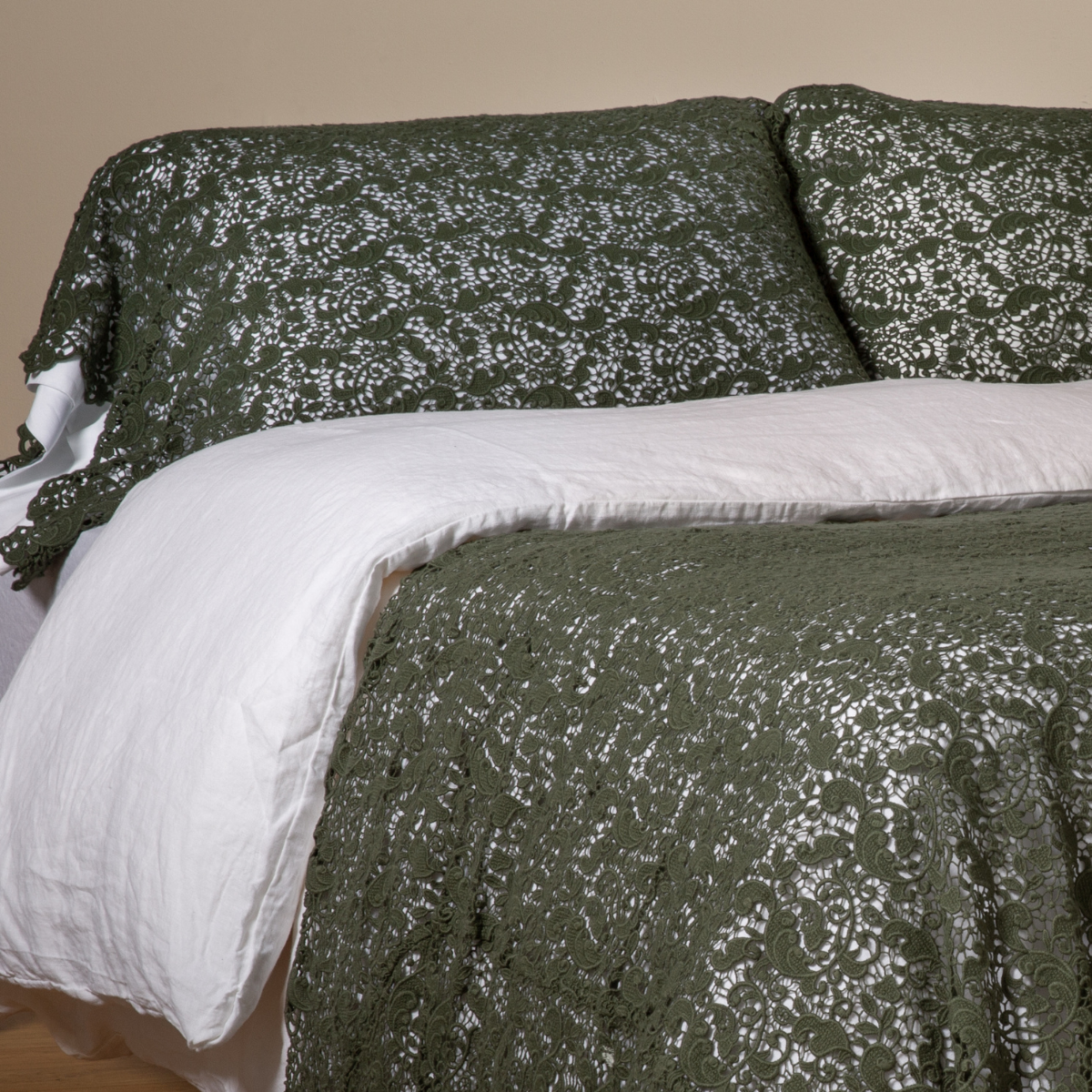 Juniper lace coverlet and shams styled on a bed with white duvet, angled view.