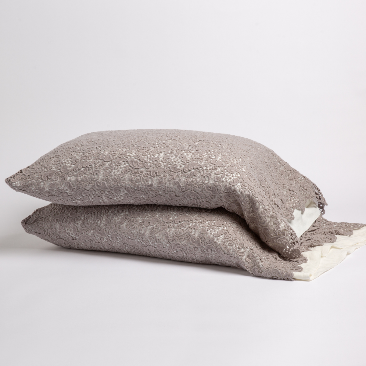 Two stacked Allora Lace pillowcases showing taupe lace texture over ivory lining, with fringe edge detail.