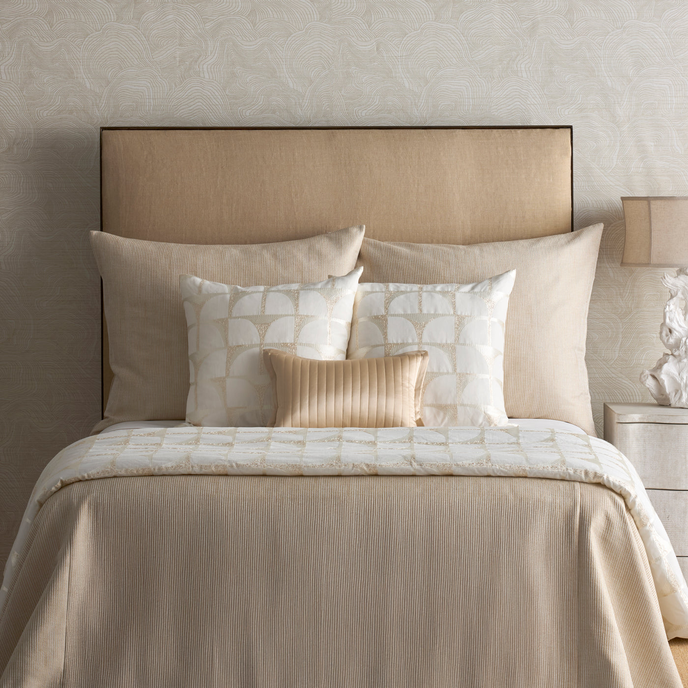Close-up of Ann Gish Arches pillow in ivory with geometric arch pattern, styled on a neutral bed.